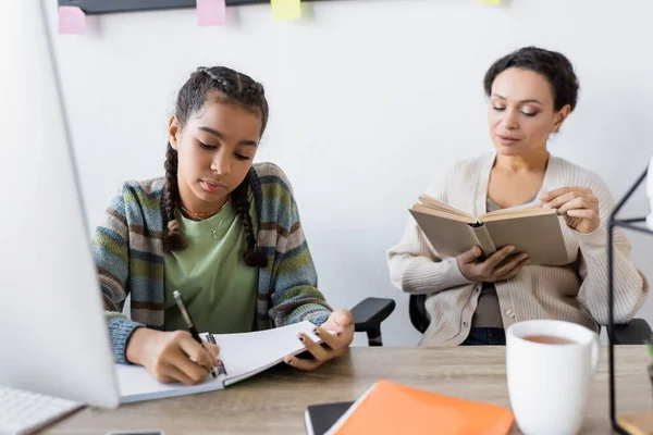 Afrikaans Amerikaans Tiener Meisje Schrijven Notebook Buurt Wazig Computer Moeder — Stockfoto