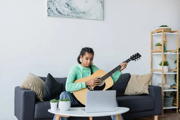 Nastoletnia Afrykańska Dziewczyna Uczy Się Grać Gitarze Pobliżu Laptopa Siedząc — Zdjęcie stockowe