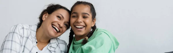兴奋的非洲裔美国女人 带着十几岁的女儿 一边笑一边在家里打着横幅 — 图库照片