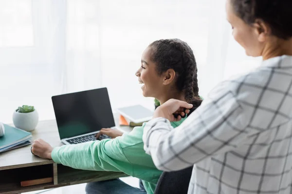 Donna Afroamericana Offuscata Intrecciare Capelli Della Figlia Sorridente Utilizzando Computer — Foto Stock