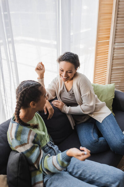 high angle view of happy african american mother and daughter talking on couch at home