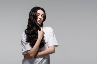 Uzun dalgalı saçları ve gri gözleri olan genç ve mutlu bir kadın.