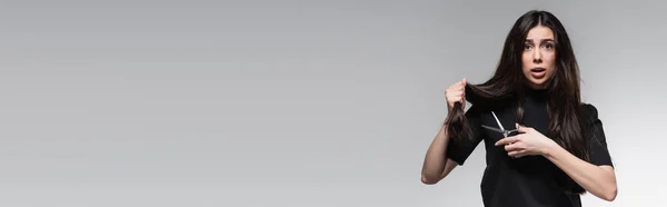 Mujer Joven Conmocionada Cuello Alto Negro Sosteniendo Tijeras Cerca Pelo — Foto de Stock