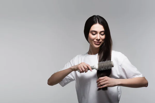 Pleased Woman Brushing Smooth Long Hair Thermal Brush Isolated Grey — Stock Photo, Image