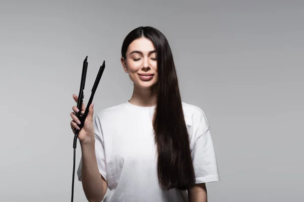 Jovem Morena Feliz Segurando Alisador Cabelo Isolado Cinza — Fotografia de Stock