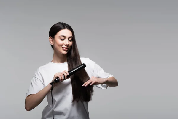 Jovem Mulher Positiva Usando Alisador Cabelo Isolado Cinza — Fotografia de Stock