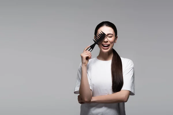 Mulher Positiva Shirt Branca Segurando Pente Perto Cabelo Liso Isolado — Fotografia de Stock