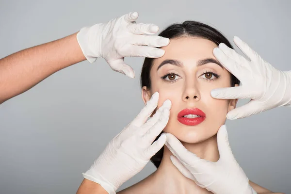 Cirurgiões Plásticos Luvas Látex Tocando Rosto Mulher Morena Isolada Cinza — Fotografia de Stock