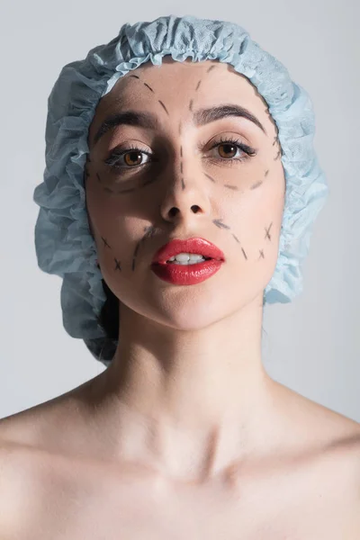 woman in surgical cap with marked lines on face isolated on grey
