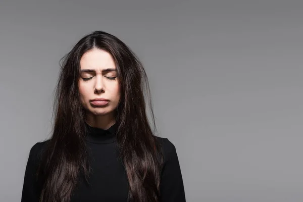 sad young woman in black turtleneck with damaged hair isolated on grey