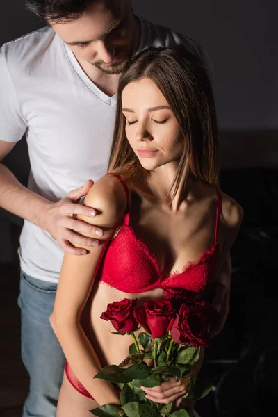 Сексуальна Жінка Червоному Бюстгальтері Тримає Букет Червоних Троянд Біля Чоловіка — стокове фото