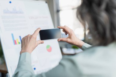 Bulanık bir iş kadınının ofiste akıllı telefondan fotoğraf çekerken görüntüsü. 