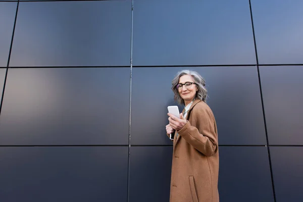 Grey Haired Businesswoman Coat Using Smartphone Holding Paper Folder Building — Stockfoto