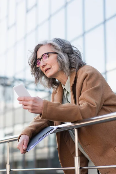Mature Manager Coat Holding Papers Using Mobile Phone Railing Urban — Stock Photo, Image