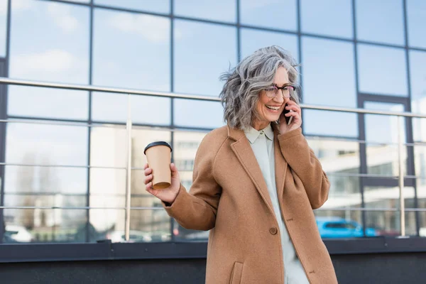 Szczęśliwa Siwowłosa Bizneswoman Rozmawiająca Przez Telefon Komórkowy Trzymająca Papierowy Kubek — Zdjęcie stockowe