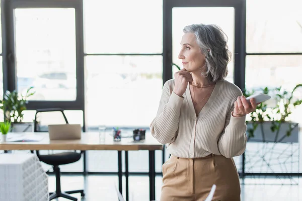 Vista Laterale Donna Affari Pensierosa Che Tiene Smartphone Vicino Modello — Foto Stock