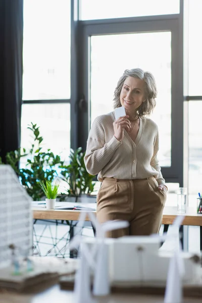 Happy Grey Haired Businesswoman Holding Mobile Phone Looking Blurred Models — Stock Photo, Image