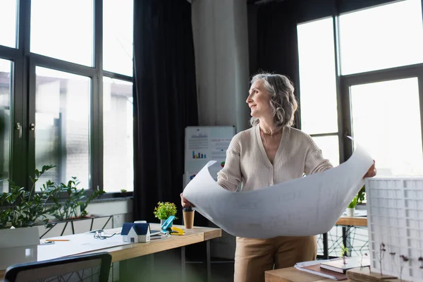 Side View Smiling Businesswoman Holding Blueprint Models Buildings Office - Stock-foto