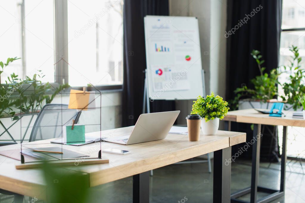 Laptop near coffee to go and papers in office 