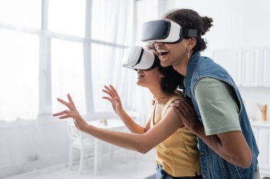 VR kulaklıklı, evde oynayan Afro-Amerikan bir çift. 