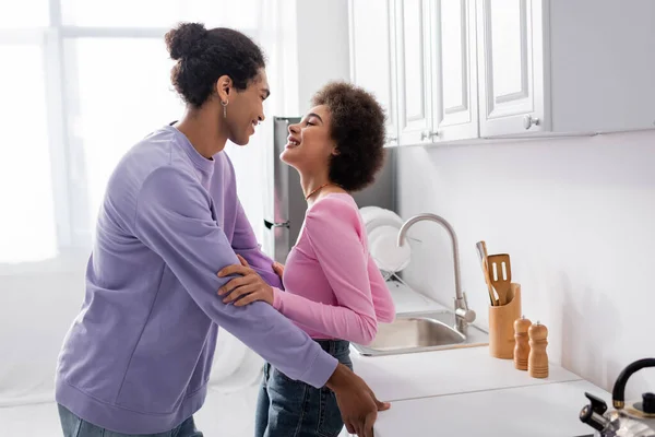 从侧面看快乐的非洲裔美国夫妇在厨房里互相望着对方 — 图库照片