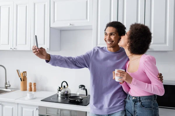 Усміхнений Американець Афроамериканець Сідає Смартфон Біля Подружки Чашкою Кухні — стокове фото