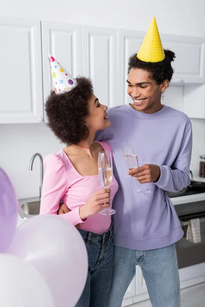 Gelukkig Afrikaanse Amerikaanse Paar Party Caps Holding Champagne Buurt Ballonnen — Stockfoto