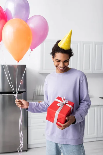 Glimlachende Afro Amerikaanse Man Met Cadeautjes Ballonnen Tijdens Verjaardagsfeestje Thuis — Stockfoto