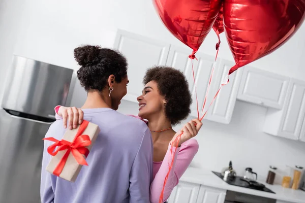 Sorrindo Afro Americana Segurando Balões Presente Abraçar Namorado Casa — Fotografia de Stock