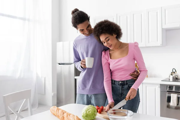 Africano Americano Hombre Celebración Taza Cerca Novia Cocinar Ensalada Casa — Foto de Stock