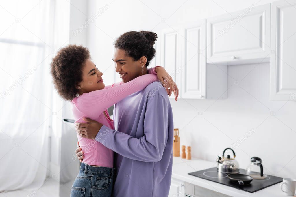 African american man embracing young girlfriend in kitchen