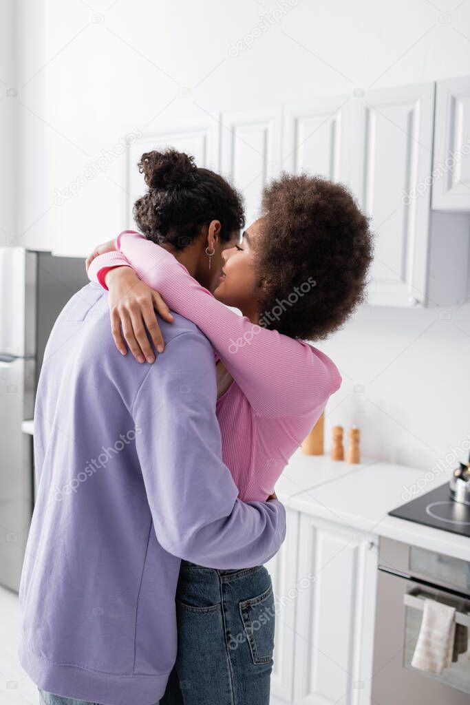 African american woman embracing and whispering to boyfriend at home 