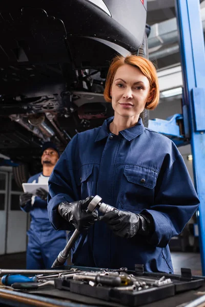 Workwoman Holding Wrench Looking Camera Blurred Colleague Car Service — Fotografia de Stock