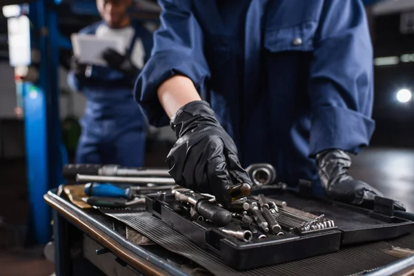 Cropped View Mechanic Gloves Taking Tool Blurred Colleague Car Service — Stock Photo, Image