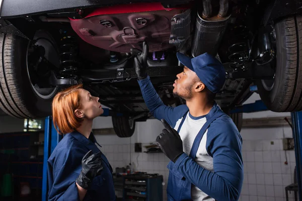 Seitenansicht Von Interracial Mechaniker Blick Auf Auto Unten Dienst — Stockfoto
