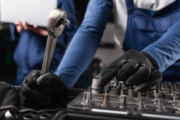 Cropped View Mechanic Holding Wrench Blurred Colleague Laptop Garage — Stock Photo, Image