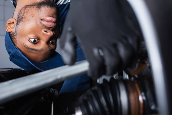african american foreman making diagnostics of car on blurred foreground