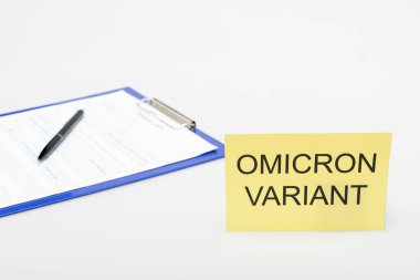 card with omicron variant lettering near clipboard with medical card and pen on grey