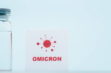 vaccine vial near card with omicron lettering and bacteria icon on blue background