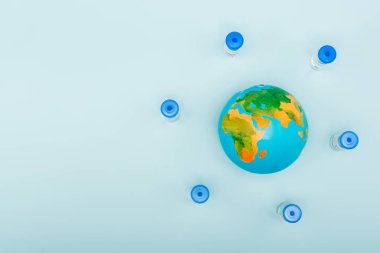 top view of vaccine bottles near globe on blue background with copy space