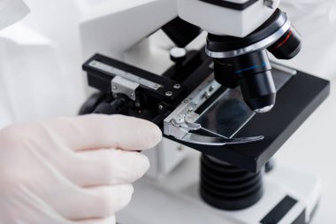 partial view of biologist working with microscope in medical laboratory