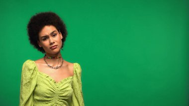 Şüpheci Afrikalı Amerikalı kadın yeşil kameraya bakıyor.