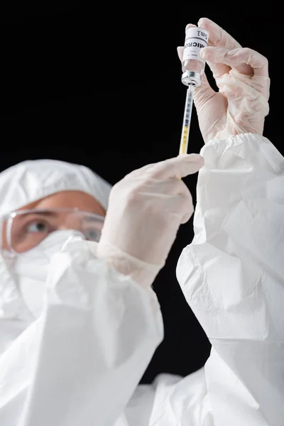 手持注射器和从黑色分离的欧米克隆变种疫苗的个人防护设备的模糊医生 — 图库照片