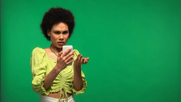 Mulher Afro Americana Descontente Usando Smartphone Isolado Verde — Fotografia de Stock