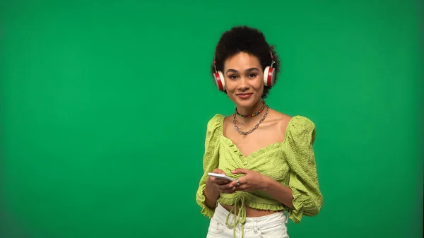 Весела Афроамериканська Жінка Блузці Бездротових Навушниках Використовуючи Смартфон Ізольовано Зеленому — стокове фото