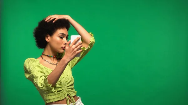 Młoda Afroamerykanka Bluzce Patrząc Smartfon Odizolowany Zielono — Zdjęcie stockowe