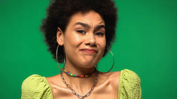 持怀疑态度的非洲裔美国女人戴着环状耳环 看着被绿色隔离的相机 — 图库照片
