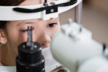 child measuring eyesight on blurred autorefractor clipart