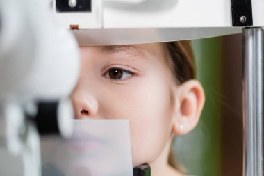 close up view of kid examining eyesight on blurred ophthalmoscope