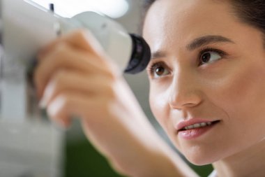 young oculist tuning ophthalmoscope on blurred foreground